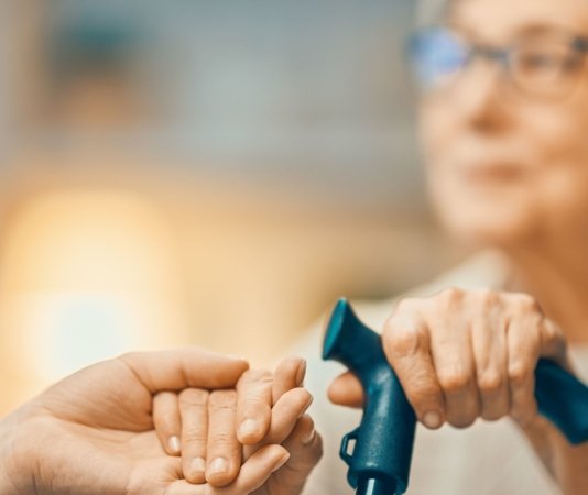 A caregiver gently holding the hand of an older adult, offering comfort and support.